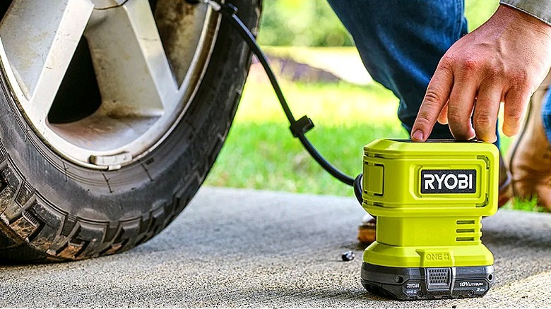 Someone using a high-pressure inflator to inflate a vehicle tire