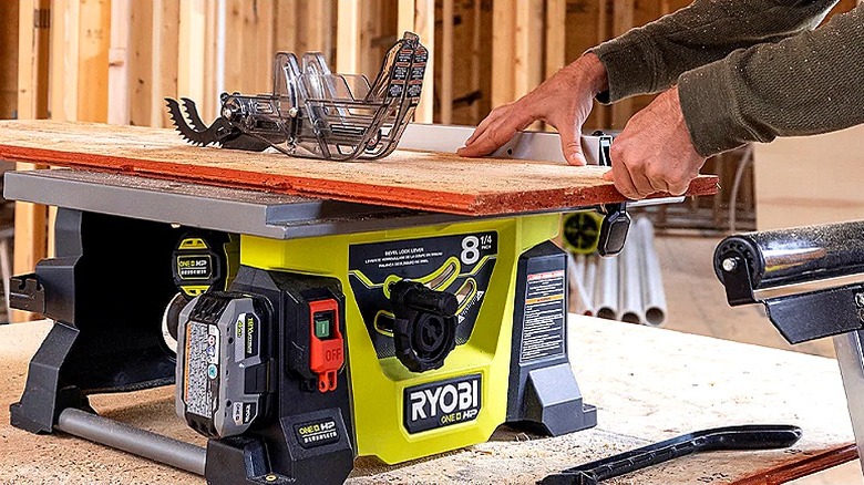 A person using a Ryobi portable jobsite table saw