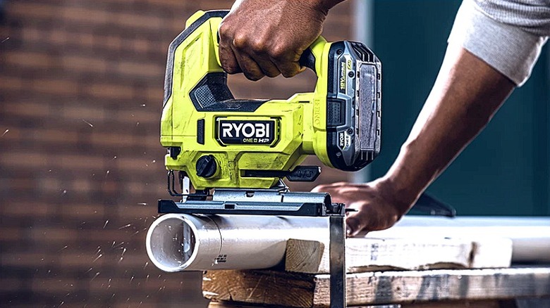 A person using a jigsaw to cut a board
