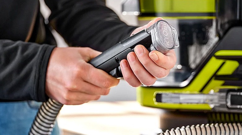 A person adjusting the nozzle on a Ryobi spot and carpet cleaner machine