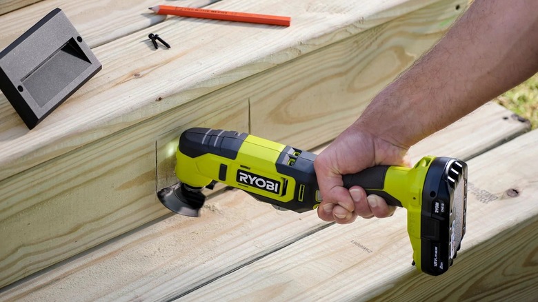Person using Ryobi oscillating tool to cut through wood