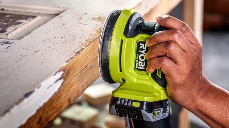 Person using Ryobi orbit sander