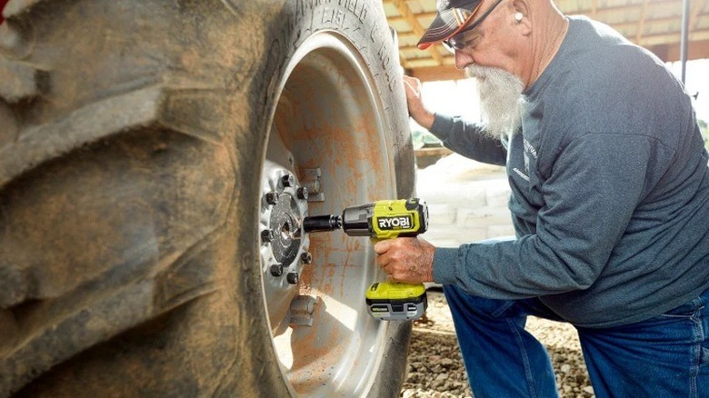 Man using a Ryobi impact wrench on a tractor tire