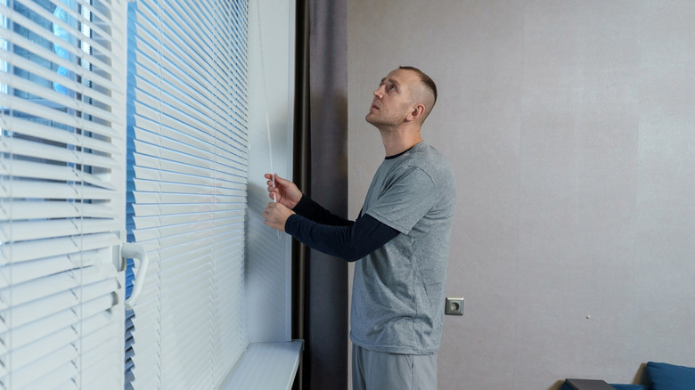 Man adjusting window blinds