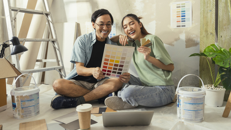Couple sitting in the floor looking at paint samples