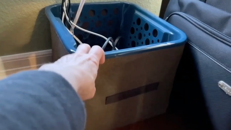 A screenshot of a Youtube video, showing a person's hand grabbing onto a basket that's used to store cords.