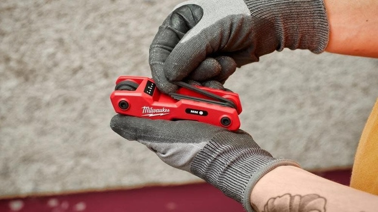 A person unfolding a key from Milwaukee's 17-Key Folding Hex Key tool