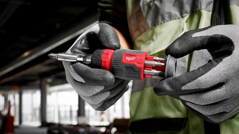 Close-up of a worker holding Milwaukee's 8-in-1 Ratcheting Compact Multi-Bit Screwdriver