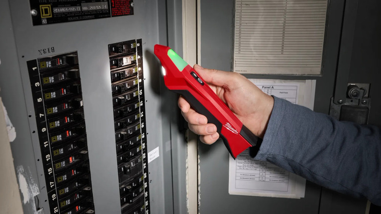 A person using Milwaukee's Circuit Breaker Finder with LED on a circuit breaker board