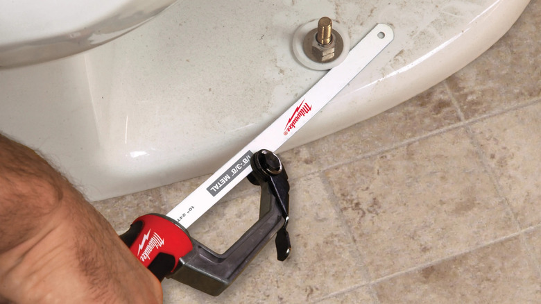 A person cutting toilet bolts with Milwaukee's Compact Hack Saw with 10-inch Bi-Metal Blade