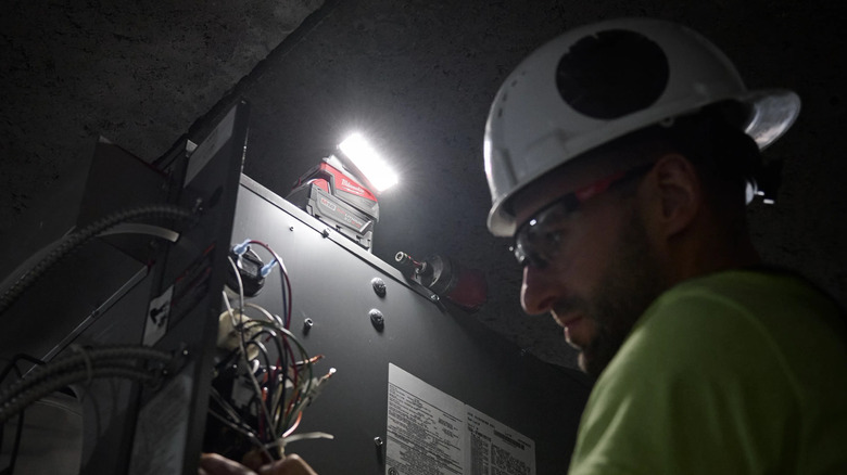 A man working with the help of Milwaukee's M18 18V Lithium-Ion Cordless 1000 Lumens ROVER Compact Folding Flood Light