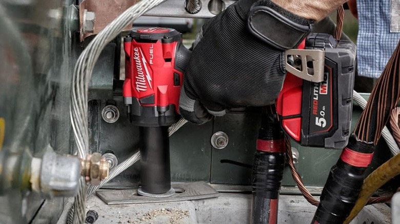 Close-up of a person removing bolts with Milwaukee's M18 FUEL GEN-3 18V Lithium-Ion Brushless Cordless ⅜-inch Compact Impact Wrench
