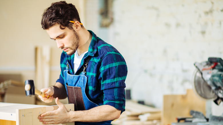 man nailing wood bench