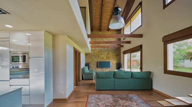 Open floor house with wood ceiling in the living area, and white ceiling in the kitchen