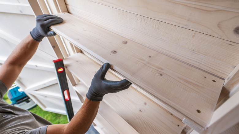 A person installing shelves on a shed wall