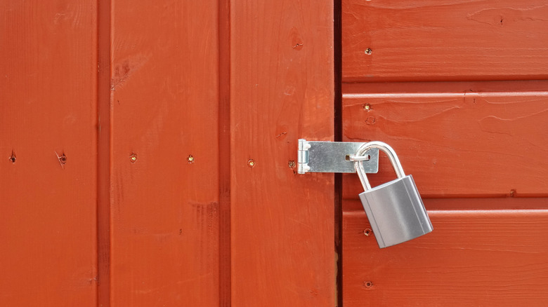 A padlock on the door of a red wood shed