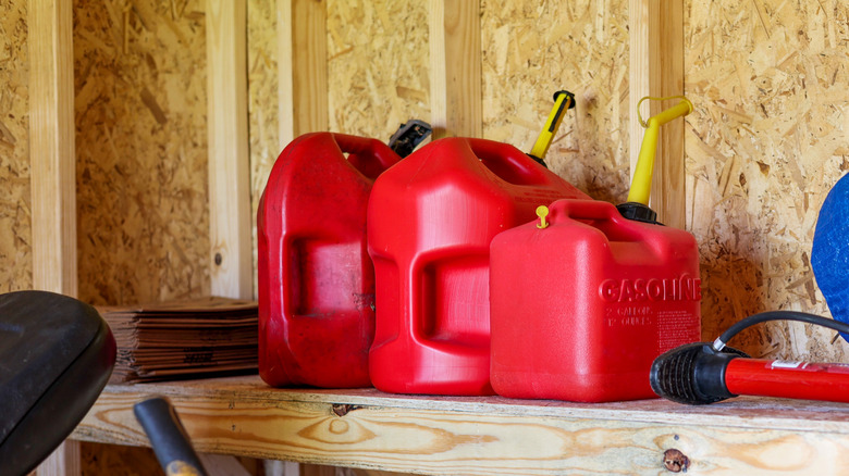 Gasoline canisters stored on a shelf inside a shed