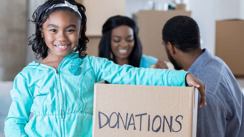 A girl holding a box with items to be donated