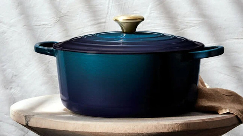 A deep blue Dutch oven on a stool with a linen backdrop