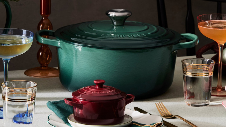 A large green and small red Dutch oven on a set table