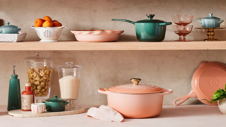 Peach and teal Le Creuset pans and glassware on shelves