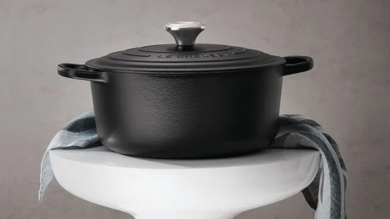 A black Le Creuset Dutch oven on a stool.