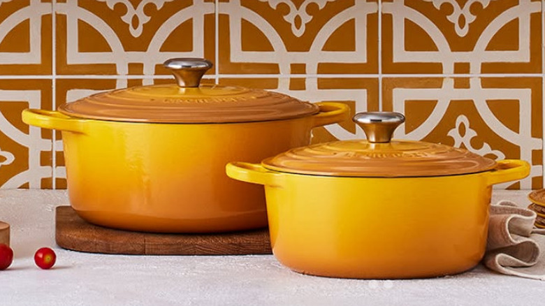 Two yellow Le Creuset Dutch ovens on a shelf