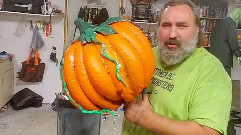A man holding a pumpkin made out of pool noodles