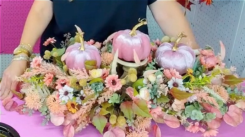 A fall centerpiece DIY display with pink pumpkins and artificial foliage
