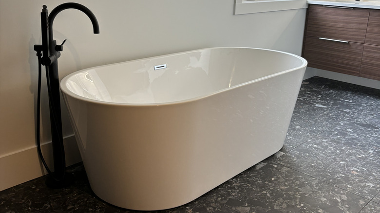 Freestanding soaking tub with black tub filler