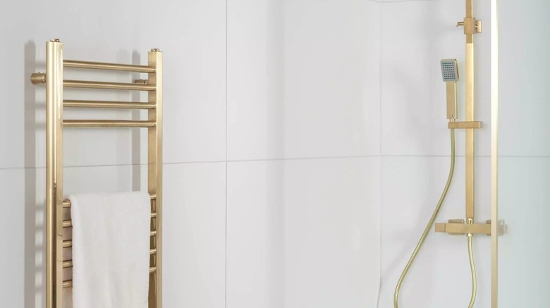Large white porcelain tiles on shower wall with brass hardware.