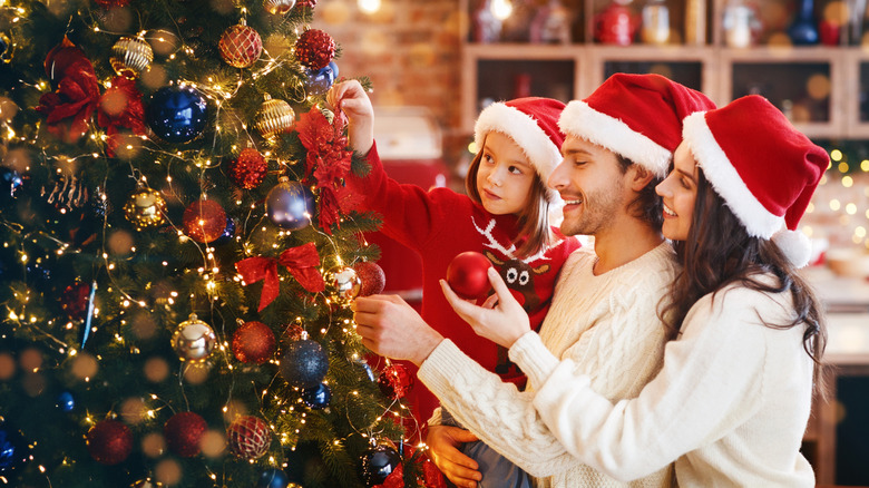 Family decorating a bold, beautiful Christmas tree