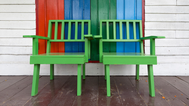Two green chairs sitting on a front porch
