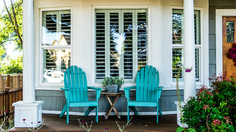 Two blue chairs sitting on a home's front porch with a small table