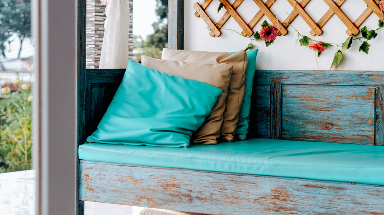 Teal and tan throw pillows sitting on wooden outdoor bench