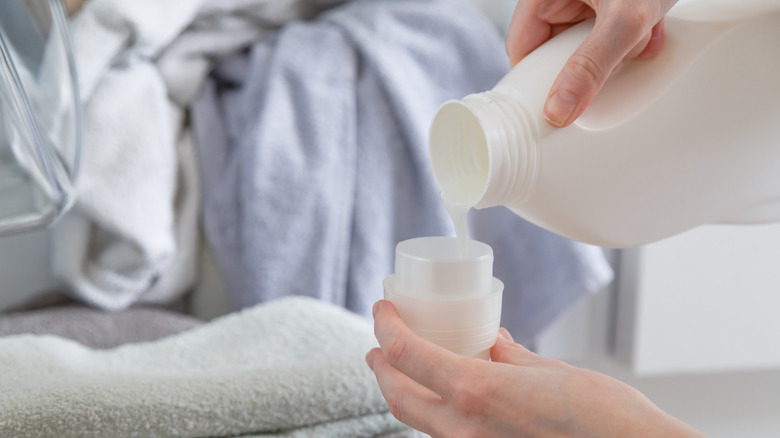 hand pouring liquid laundry detergent