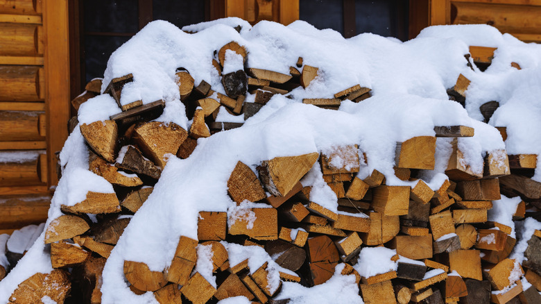wood piled outside house in the snow