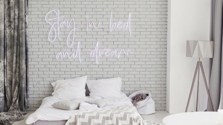 A "stay in bed and dream" neon sign above a bed