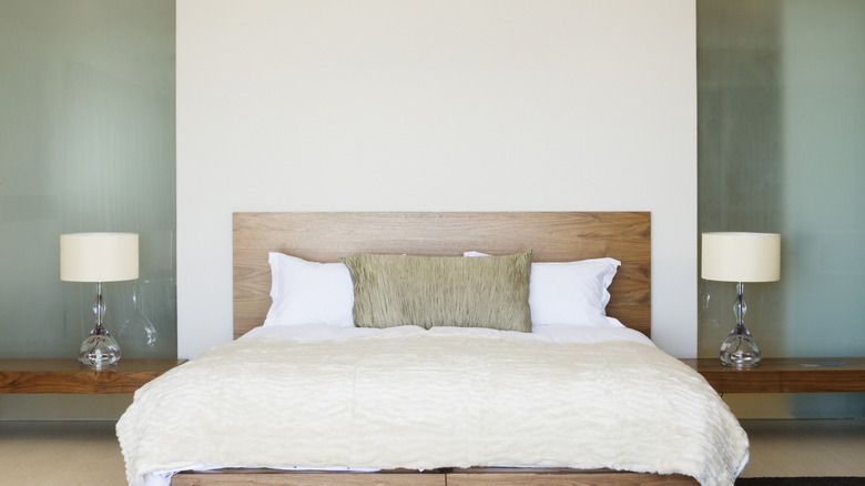 bed with two bedside lamps and empty wall above the headboard