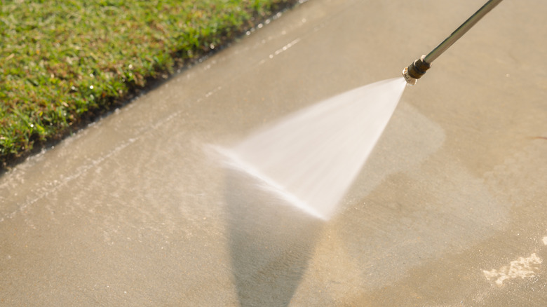 Pressure washing spray next to lawn