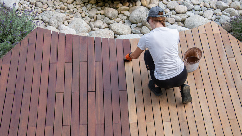 Person applying sealer to a wood deck