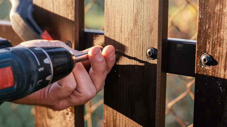 Person repairing a wood fence