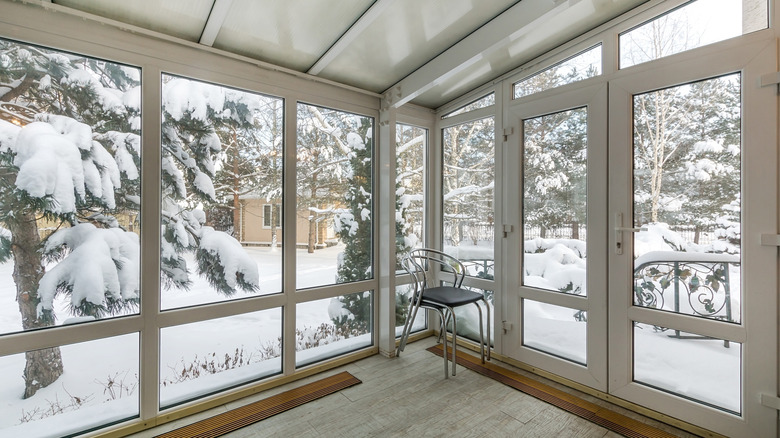 View of a snowy backyard from an enclosed porch