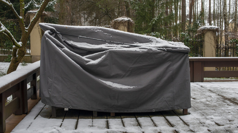 Patio furniture with a cover over it and a light dusting of snow