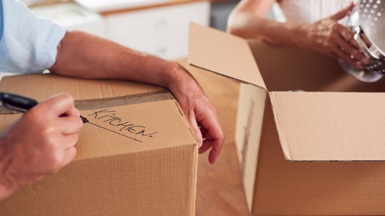 person writing kitchen on box