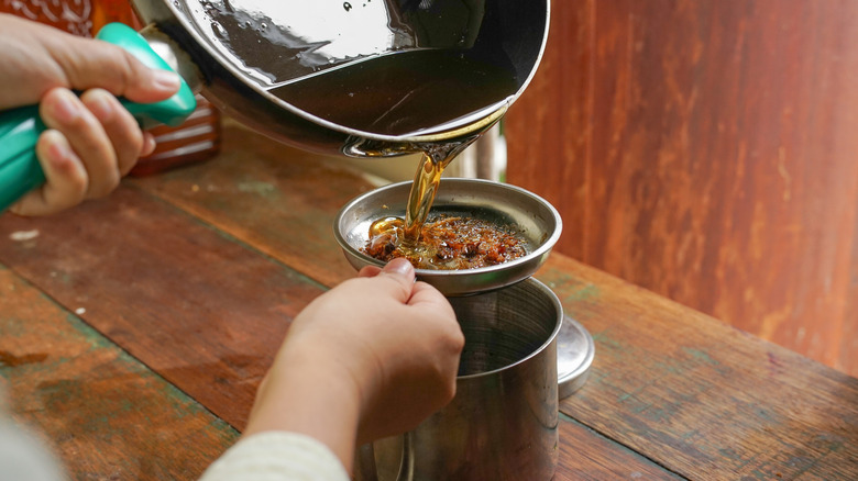 Pouring used cooking oil through a sieve