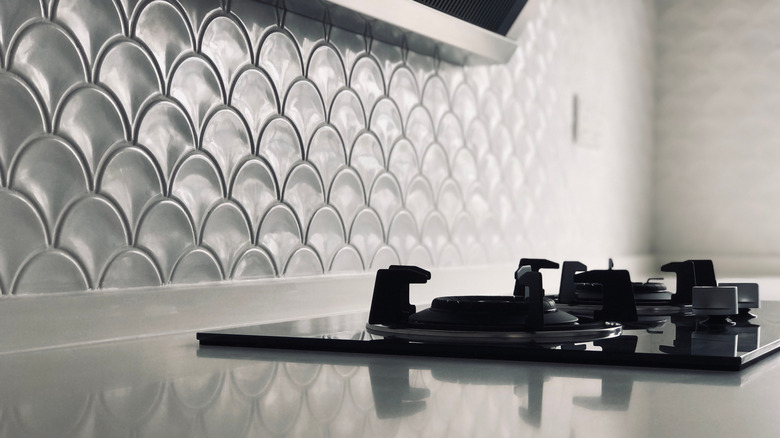 A countertop gas range with a white fish scale tile backsplash.