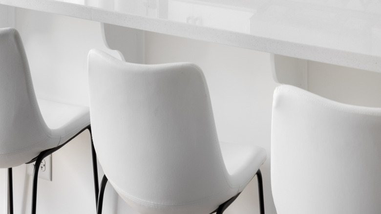 A white kitchen with a white and gold geometric backsplash and black accents.