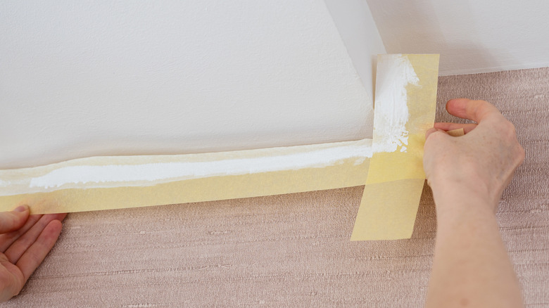 Painting tape being used along a white wall