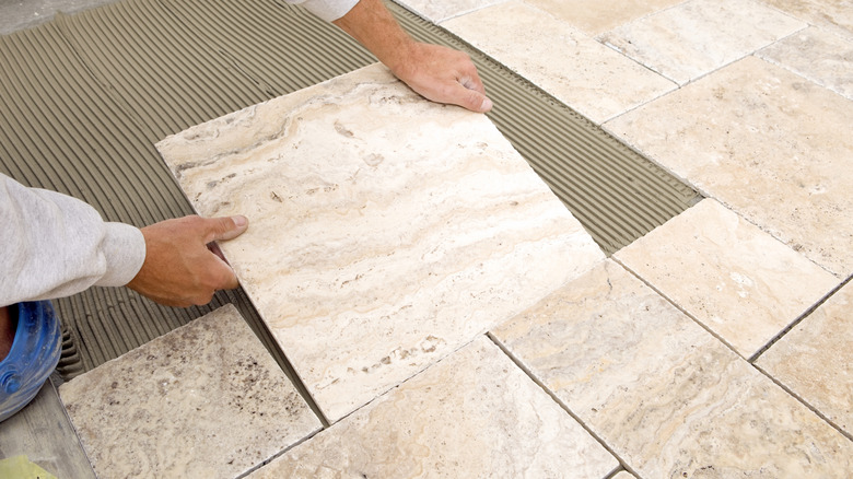 A man laying stone floor tiles